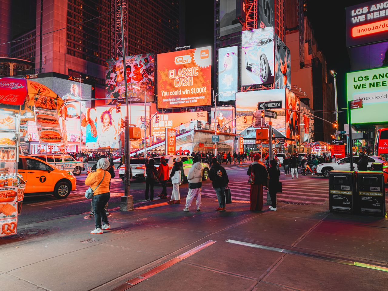 Bustling nighttime in Times Square, with bright advertisements and diverse crowd in New York City.