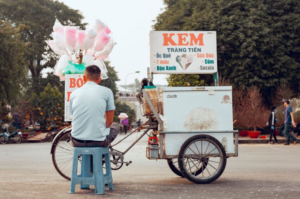 The Art of Drawing Readers In: Your attractive post title goes here Man sitting by a colorful cotton candy cart in an outdoor market setting.